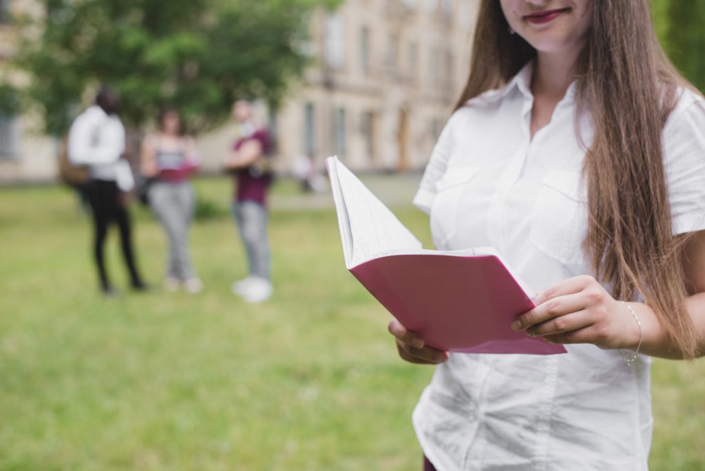 girl holding open notebook standing